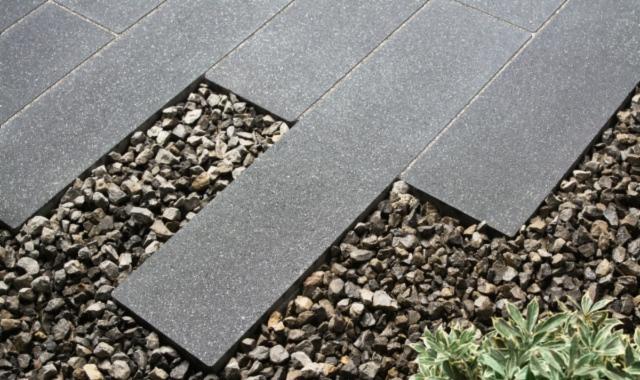 Szara kostka brukowa ułożona wzdłuż ścieżki z ozdobnym żwirem i roślinnością w Kadzidło.