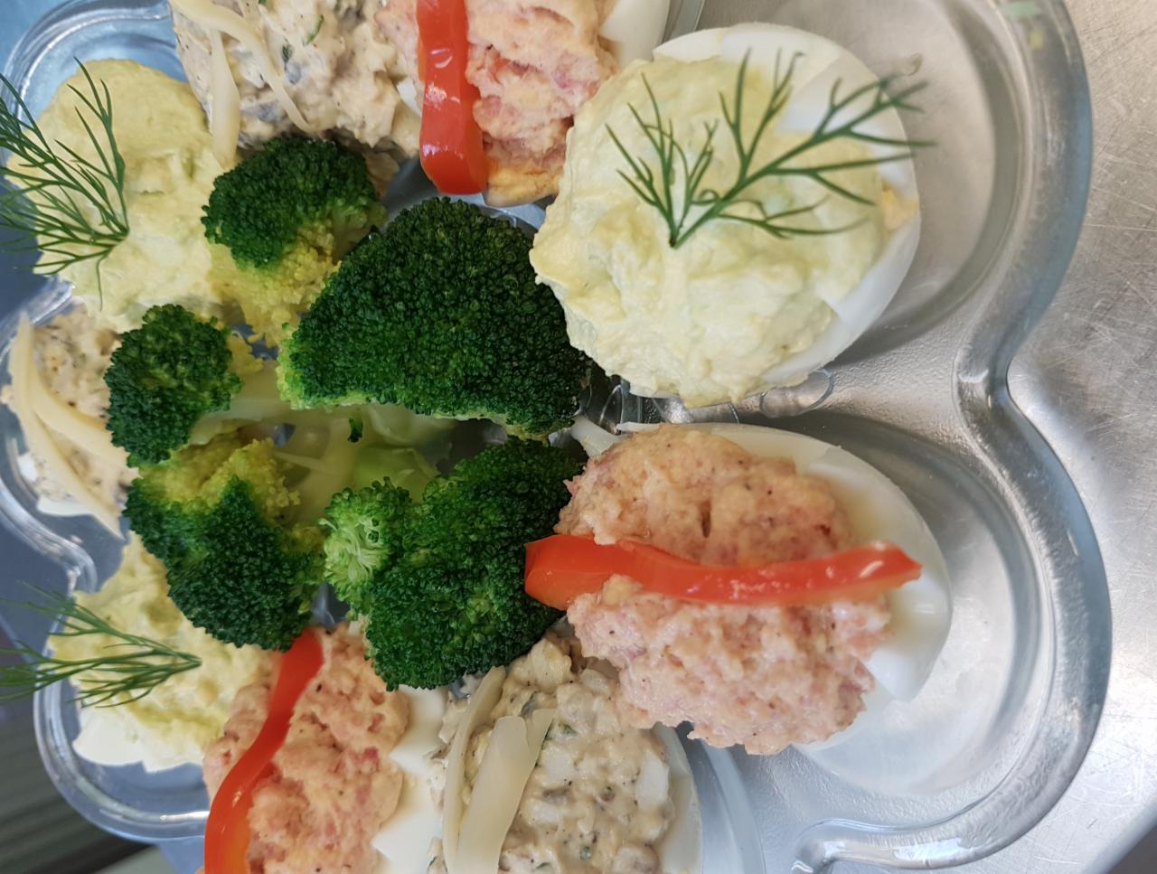 Elegancko podane jajka faszerowane z brokułami i dekoracją z koperku na szklanym półmisku.