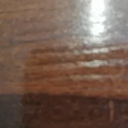 Rozmazane ujęcie lakierowanej, drewnianej powierzchni z widocznym odbiciem światła.