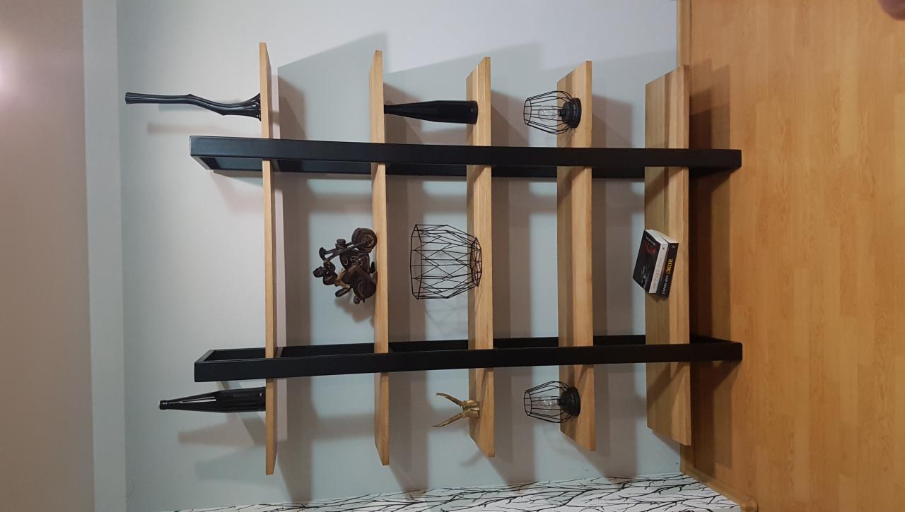 Nowoczesna, drewniana półka z czarnymi elementami w Bolmin, dekorowana ozdobnymi przedmiotami, książką i lampkami.