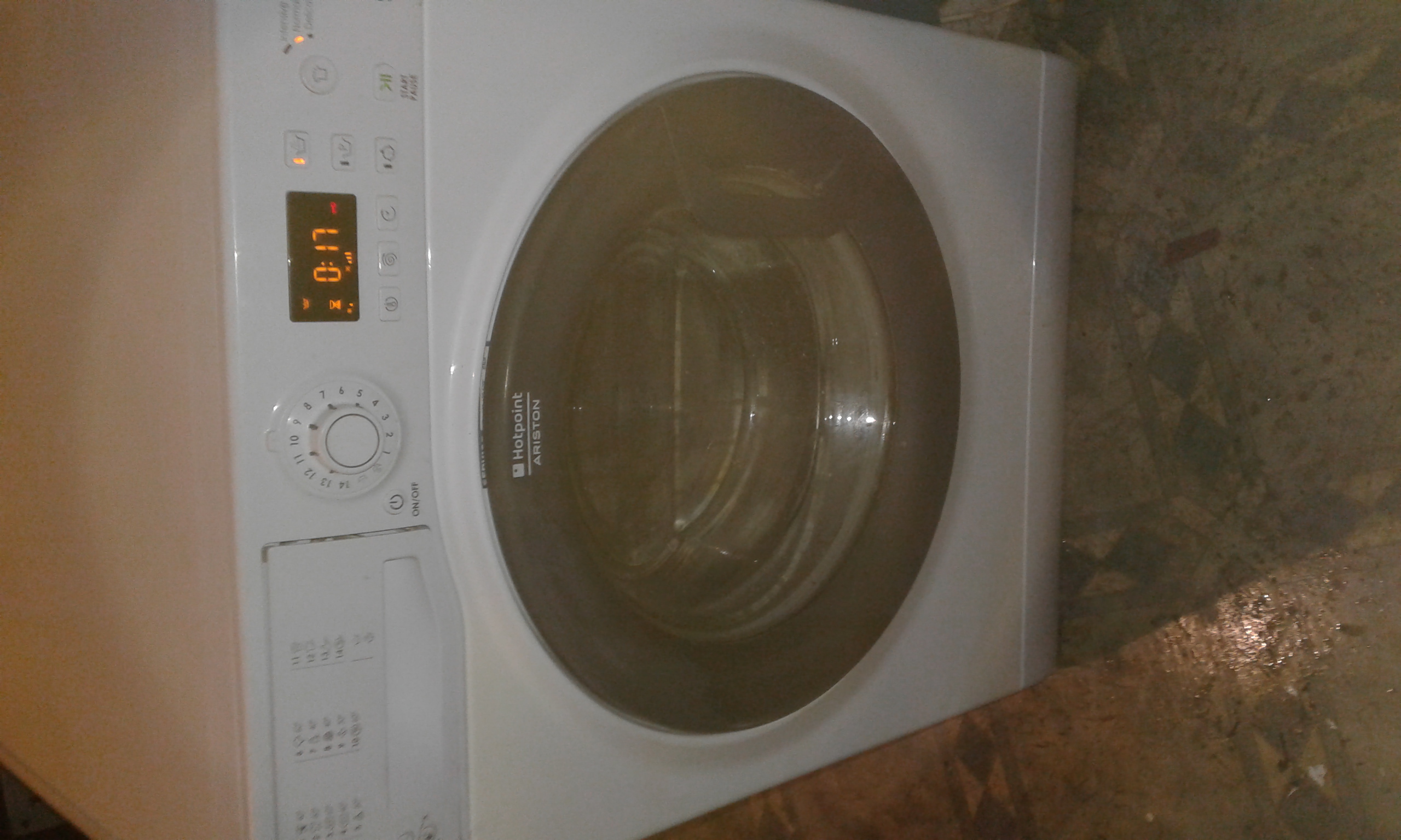 Pralka Hotpoint Ariston z włączonym panelem sterowania, wyświetlającym czas 0:17, ustawiona na nierównej podłodze.