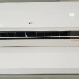 Biała jednostka klimatyzacji Midea zamontowana na ścianie, wyświetlająca temperaturę 30 stopni Celsjusza.