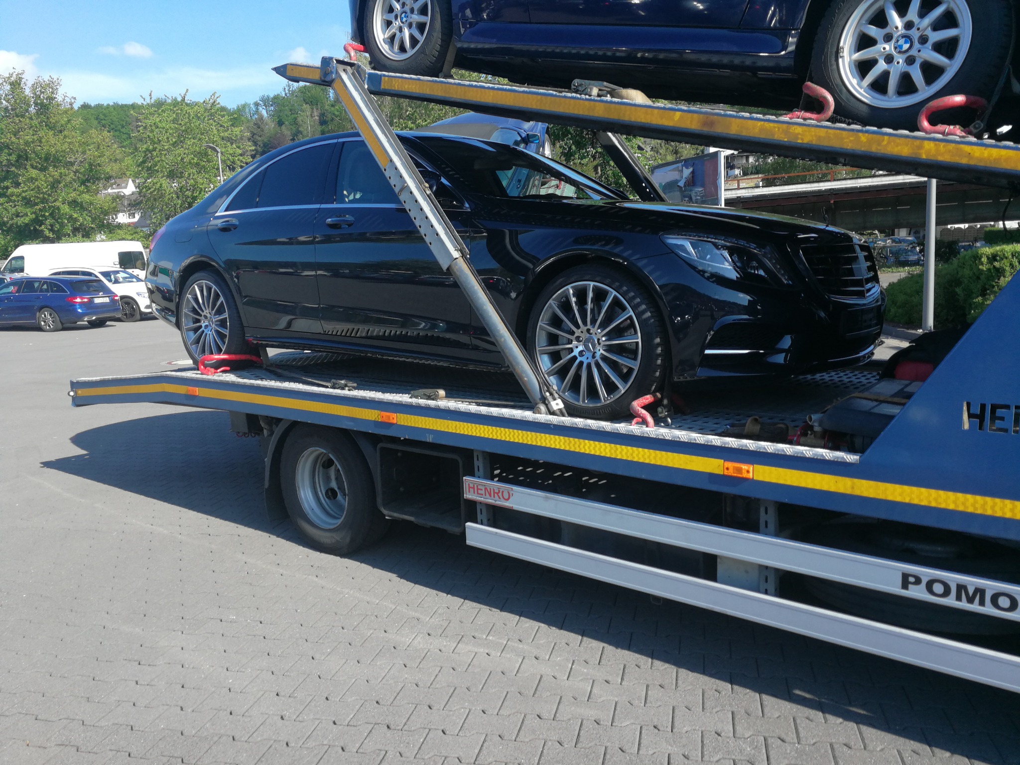 Czarny Mercedes-Benz klasy S bezpiecznie umieszczony na lawecie w Karśnicach, widoczne pasy zabezpieczające koła, na górnym poziomie lawety drugi samochód.