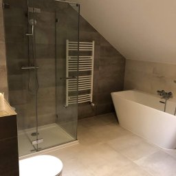 Adam Grygo - Nowoczesna łazienka na poddaszu z kabiną prysznicową ze szklanymi drzwiami, grzejnikiem drabinkowym i wolnostojącą wanną.