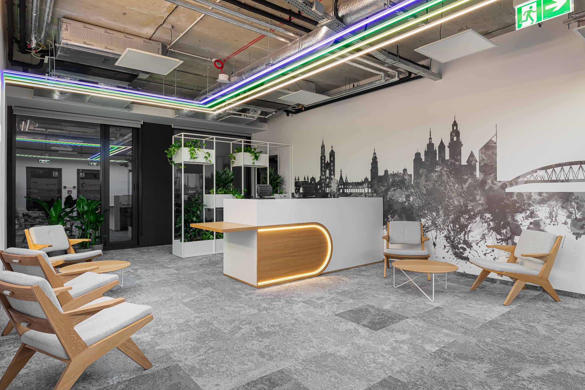 Nowoczesne biuro z recepcją, podświetlanym blatem z drewna i tapetą z panoramą miasta, uzupełnione drewnianymi fotelami z szarą tapicerką.