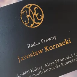 Wizytówka radcy prawnego Jarosława Kornackiego, z tłoczonym złotym logo i danymi kontaktowymi na ciemnym tle.