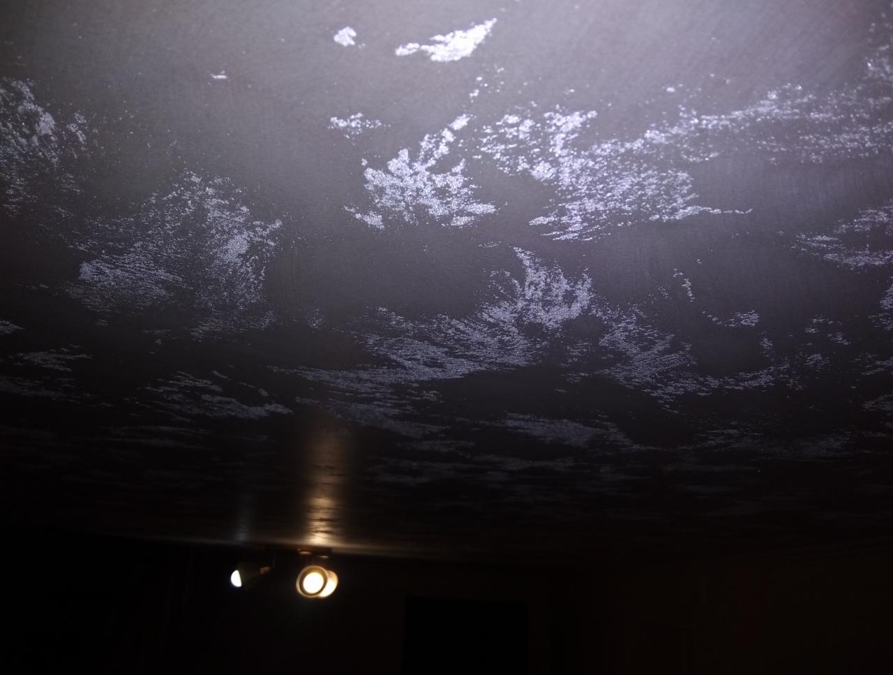 Ciemny sufit z dekoracyjną, nieregularną fakturą przypominającą chmury, oświetlony przez dwa halogenowe reflektory.