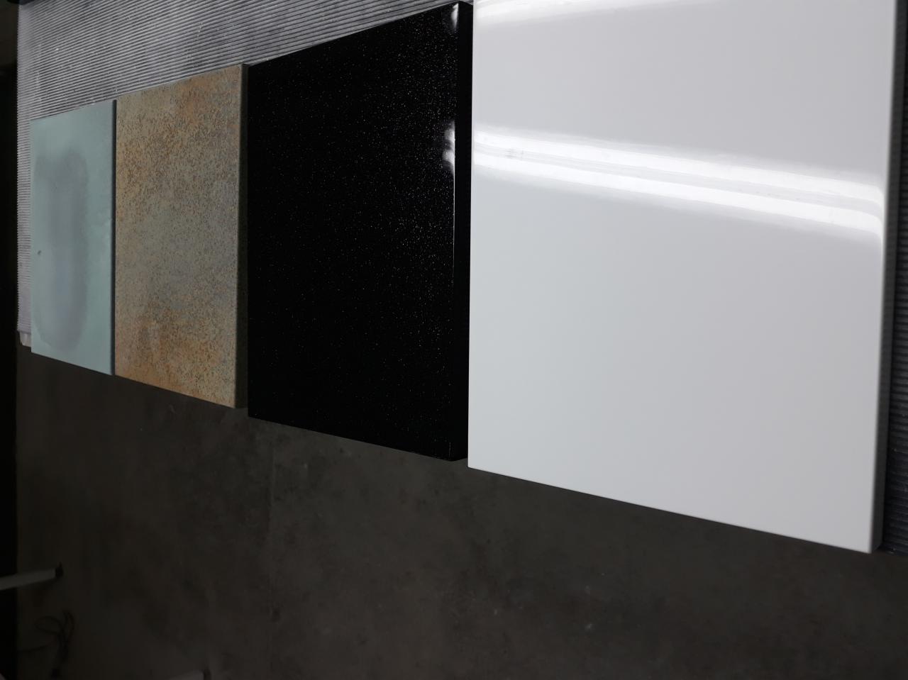 Próbki tapicerki meblowej: jasnoniebieska, rdzawa, czarna z połyskiem i biała, ułożone obok siebie na szarym tle.