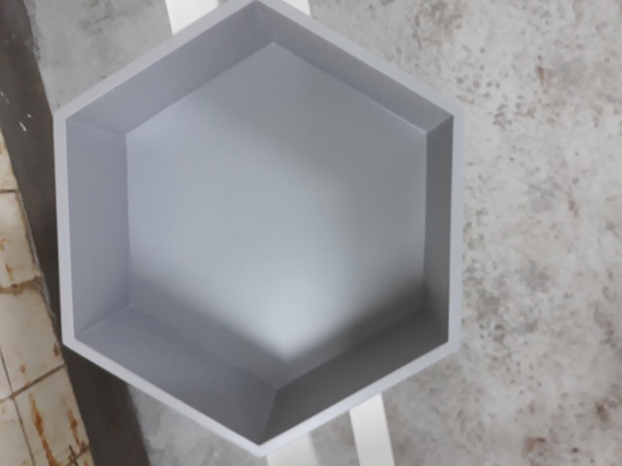 Sześciokątna, pomalowana na szaro półka, widok z góry, ukazująca wnętrze i krawędzie, na tle szarej podłogi.