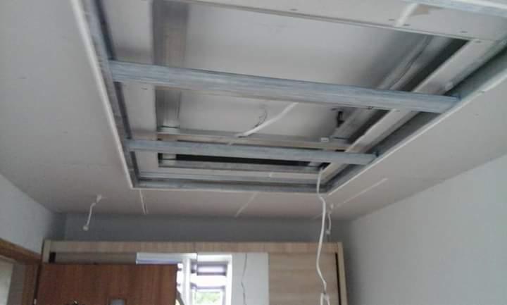 Montaż podwieszanego sufitu z płyt karton gips na metalowej konstrukcji, widoczne przewody elektryczne.