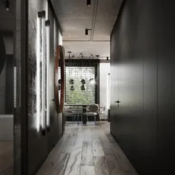 Długi korytarz w ciemnej tonacji z drewnianą podłogą, okrągłym lustrem i pionowymi lampami LED na ścianie, w tle widoczny stół z krzesłami przy oknie.