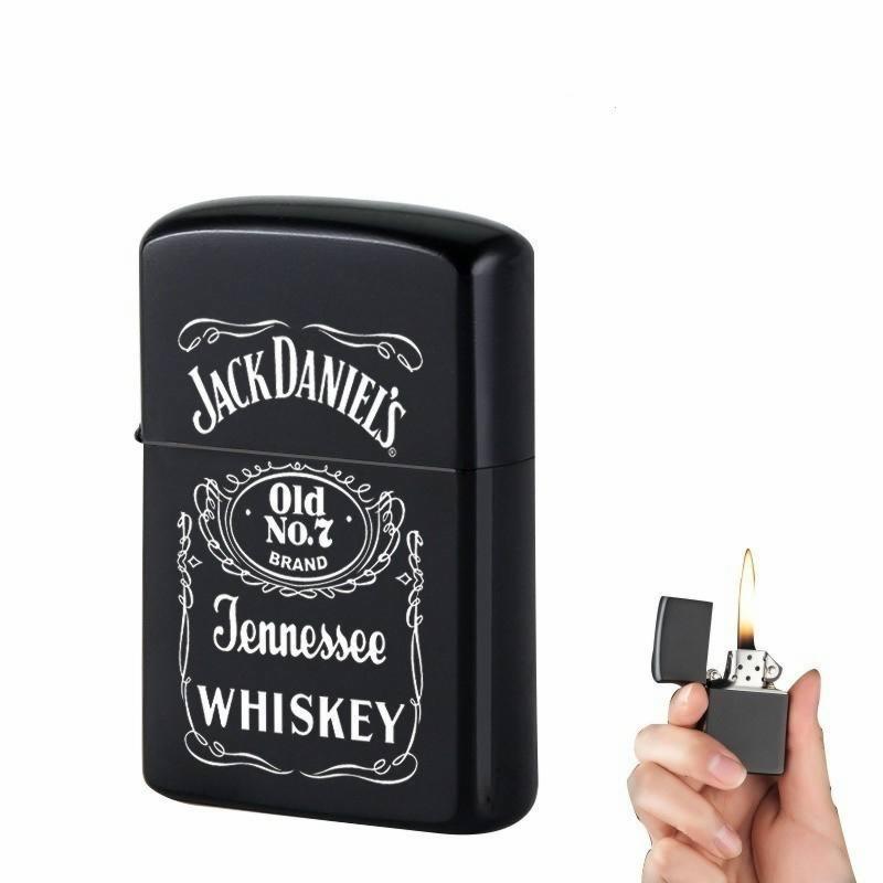 Czarna zapalniczka z białym nadrukiem Jack Daniel's Tennessee Whiskey, obok druga zapalniczka w dłoni z płomieniem.