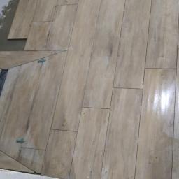 Korta - Układanie podłogi z płytek imitujących drewno, z widocznym odpływem liniowym w rogu pomieszczenia. Użyto klipsów poziomujących.