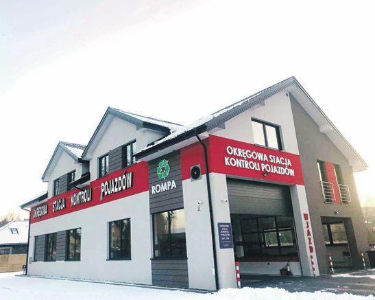 Budynek Okręgowej Stacji Kontroli Pojazdów ROMPA z logo z symbolem recyklingu, w zimowej scenerii.