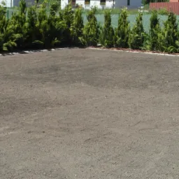 Przygotowany teren pod trawnik, z nasadzeniami tuj wzdłuż ogrodzenia, widok z góry.