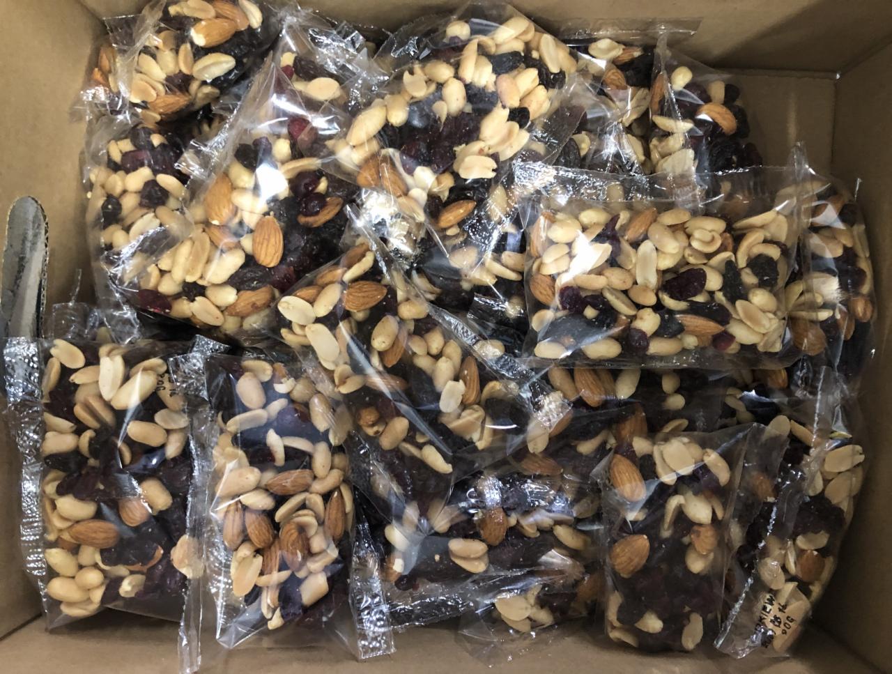 Paczki z mieszanką orzechów i suszonych owoców, zapakowane w przezroczyste foliowe woreczki, umieszczone w kartonowym pudełku.