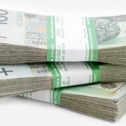 Stos ułożonych banknotów 100 zł z banderolami Narodowego Banku Polskiego, widoczne numery seryjne i nominały.