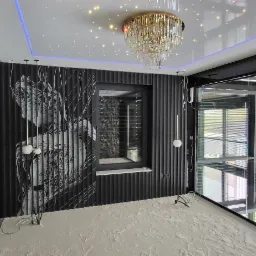 Nowoczesne wnętrze z czarną ścianą z grafiką, podwieszanym sufitem z oświetleniem LED i kryształowym żyrandolem, w trakcie wykańczania podłogi.