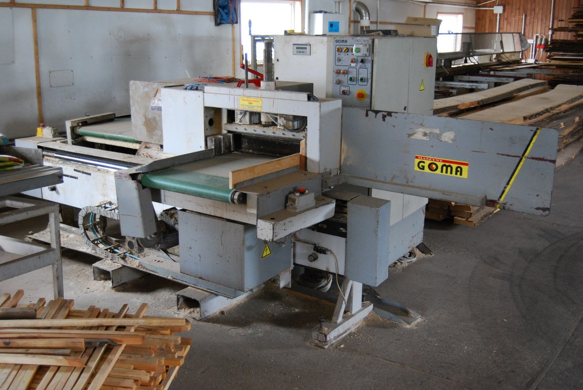 Linia do obróbki drewna Goma FC-10 KZ6 + FC-10 PZ6/2 z zielonym pasem transmisyjnym, widoczne elementy sterujące i składowane deski.