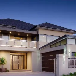 Dwukondygnacyjny dom z balkonem, oświetlony zewnętrznymi lampami, z garażem i numerem domu 28 przy wejściu, sfotografowany o zmierzchu.