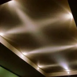 Podwieszany sufit z oświetleniem punktowym, ciepłe światło tworzące geometryczne wzory na powierzchni.