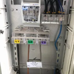 Rozdzielnica elektryczna z bezpiecznikiem RBK 00 firmy Apator, widoczne przewody fazowe L1, L2, L3 oraz tabliczka informacyjna z danymi technicznymi i oznaczeniem Energa 2017.