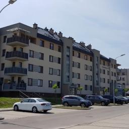 Izol-Mont Sp. z o.o. - Nowoczesny budynek mieszkalny z balkonami w Rzeszowie, zlokalizowany przy parkingu z zaparkowanymi samochodami.