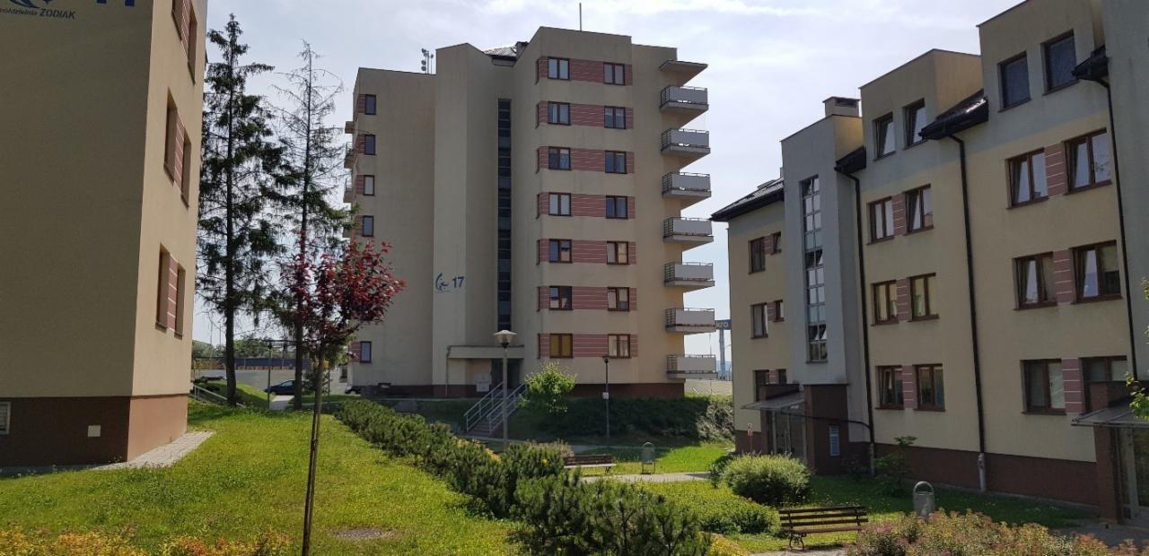 Nowoczesny budynek mieszkalny z balkonami, numer 17, otoczony zielenią i drzewami.