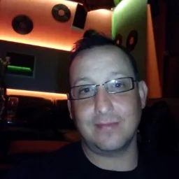 Mężczyzna w okularach robiący selfie w barze z dekoracjami w stylu retro i grami