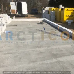 Budowa domu z bloczków Ytong: widok na fundamenty i początek wznoszenia ścian, z zaparkowanym białym vanem w tle.