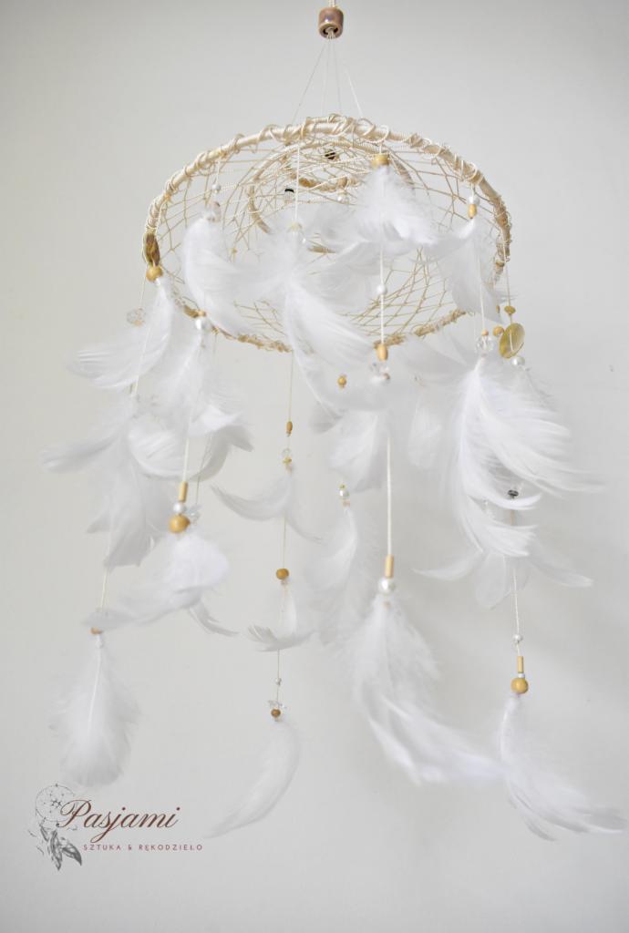 Ręcznie robiony łapacz snów z białymi piórami, drewnianymi i szklanymi koralikami, zawieszony na tle białej ściany, z widocznym logo 'Pasjami - Sztuka i Rękodzieło'.