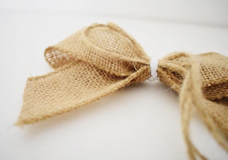Kokarda z juty, zabezpieczona białą gumką recepturką, na białym tle.