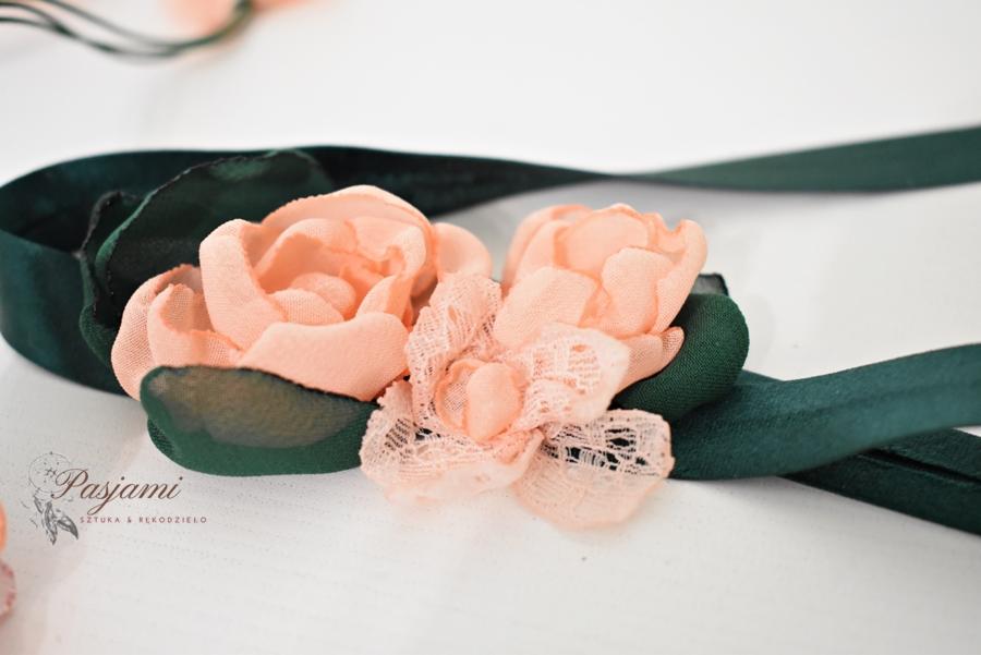 Dekoracja z materiałowych, brzoskwiniowych kwiatów i ciemnozielonej wstążki na białym tle, z widocznym logo 'Pasjami Sztuka & Rękodzieło'.