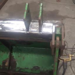 FHU Agtrans-express - Fragment zielonej łyżki koparki po naprawie, widoczne nowe spawy i ślady zużycia farby.