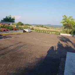 Przygotowany teren pod trawnik z widocznymi rabatami kwiatowymi i systemem nawadniania, w tle krajobraz wiejski.