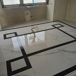 Podłoga wyłożona białymi płytkami z czarnym geometrycznym wzorem w nowym pomieszczeniu, widoczne wystające kable instalacji elektrycznej i okno z planem architektonicznym.