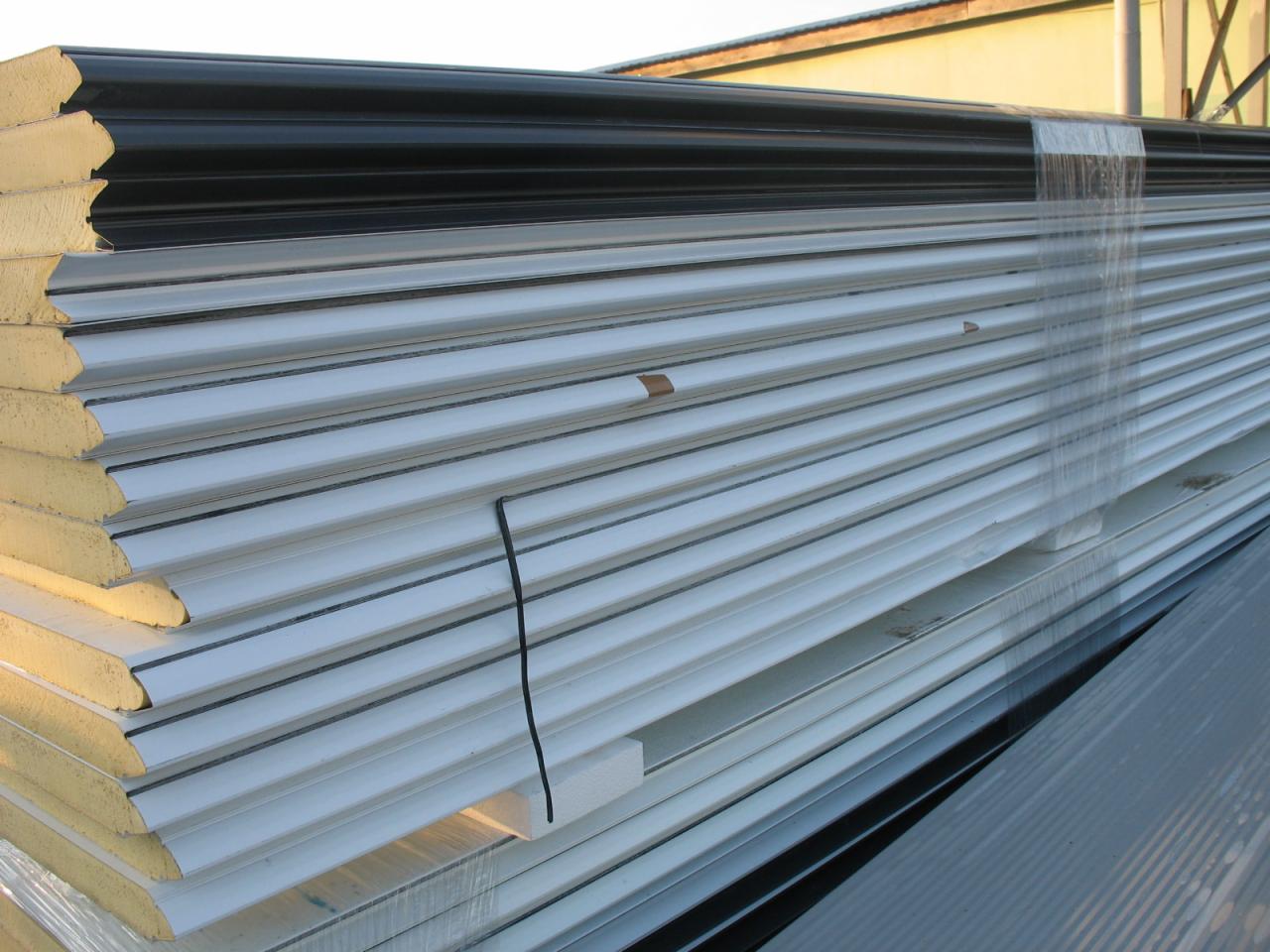 Stos płyt warstwowych z rdzeniem piankowym, zabezpieczonych folią i spiętych czarnym sznurkiem, widoczne od strony krawędzi i powierzchni.