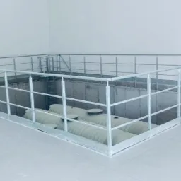 Metalowa balustrada zabezpieczająca otwór w podłodze, widoczne zbiorniki pod spodem, szara podłoga, białe ściany, na palecie leży urządzenie Tekleen.