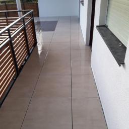 Usługi Remontowo-Budowlane Mateusz Pacuła - Wyłożony beżowymi płytkami taras z drewnianą balustradą, widok z góry, jasne oświetlenie.