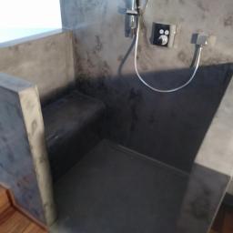 Usługi Remontowo-Budowlane Mateusz Pacuła - Betonowa kabina prysznicowa z siedziskiem, chromowana armatura, surowy industrialny styl, podłoga z drewnianych desek.