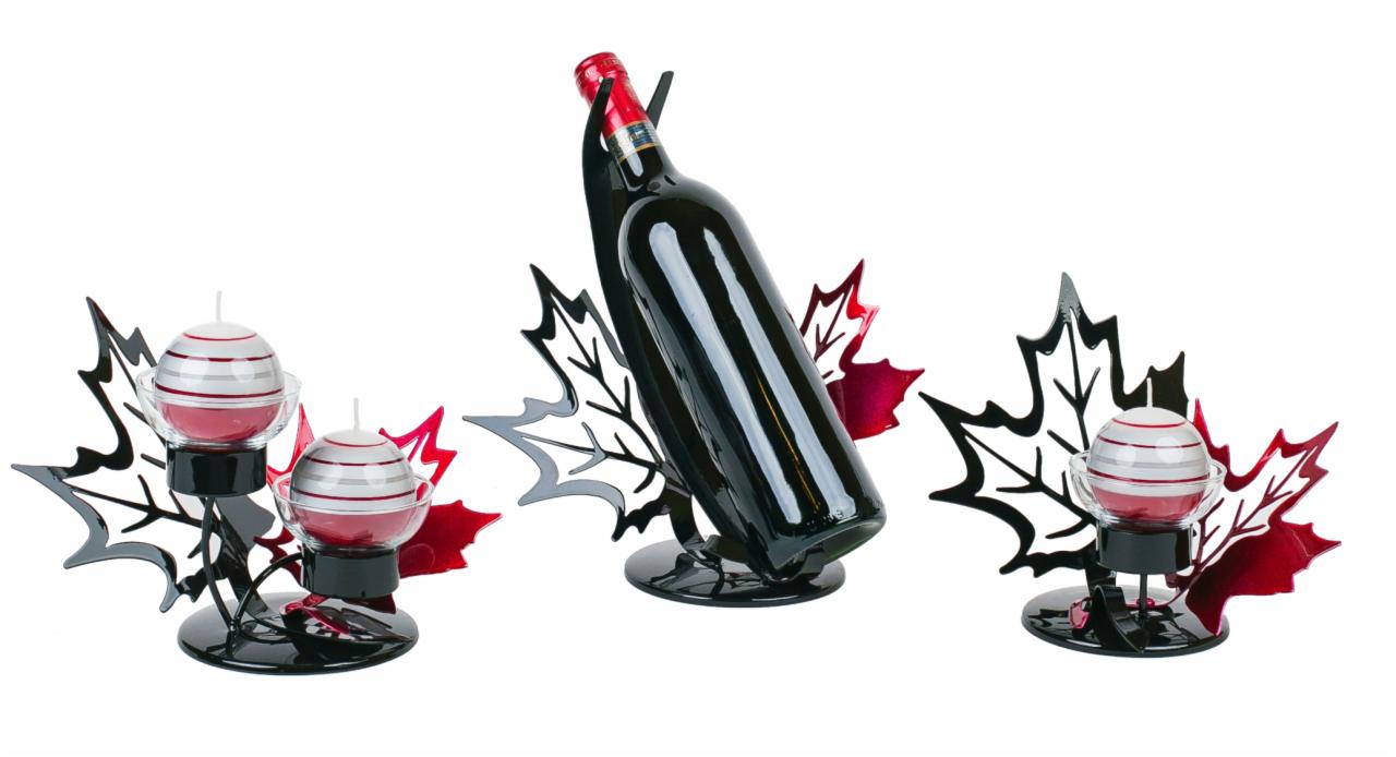 Metaloplastyka: zestaw świeczników kulistych i stojaka na wino z motywem liści klonu, malowane na czarno i czerwono, na białym tle.