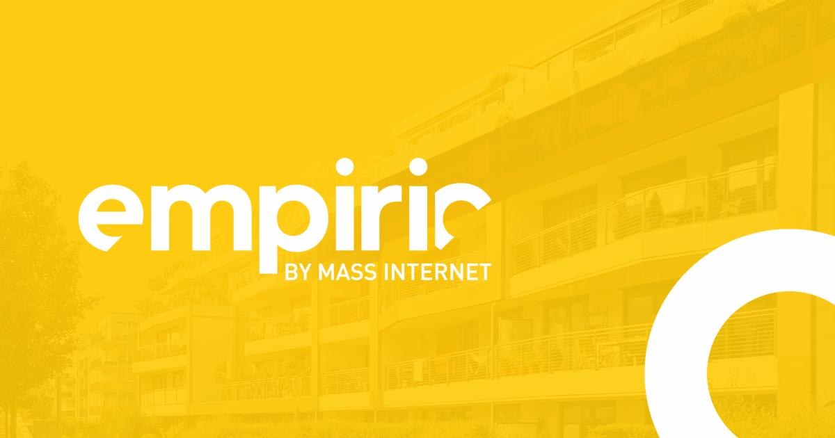Żółte tło z białym napisem 'empiric by MASS INTERNET' na tle budynku mieszkalnego.