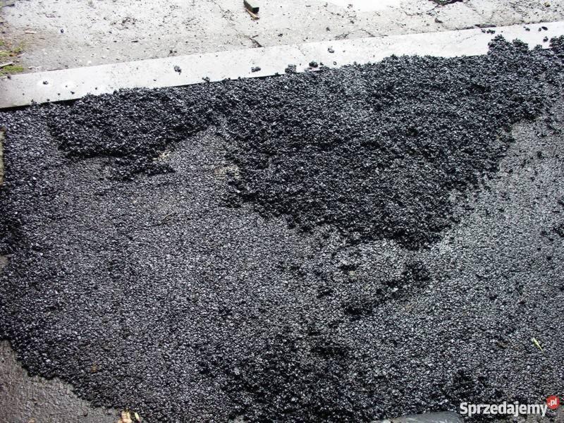 Świeżo rozłożona, czarna nawierzchnia asfaltowa z widocznym fragmentem metalowej listwy krawężnikowej.