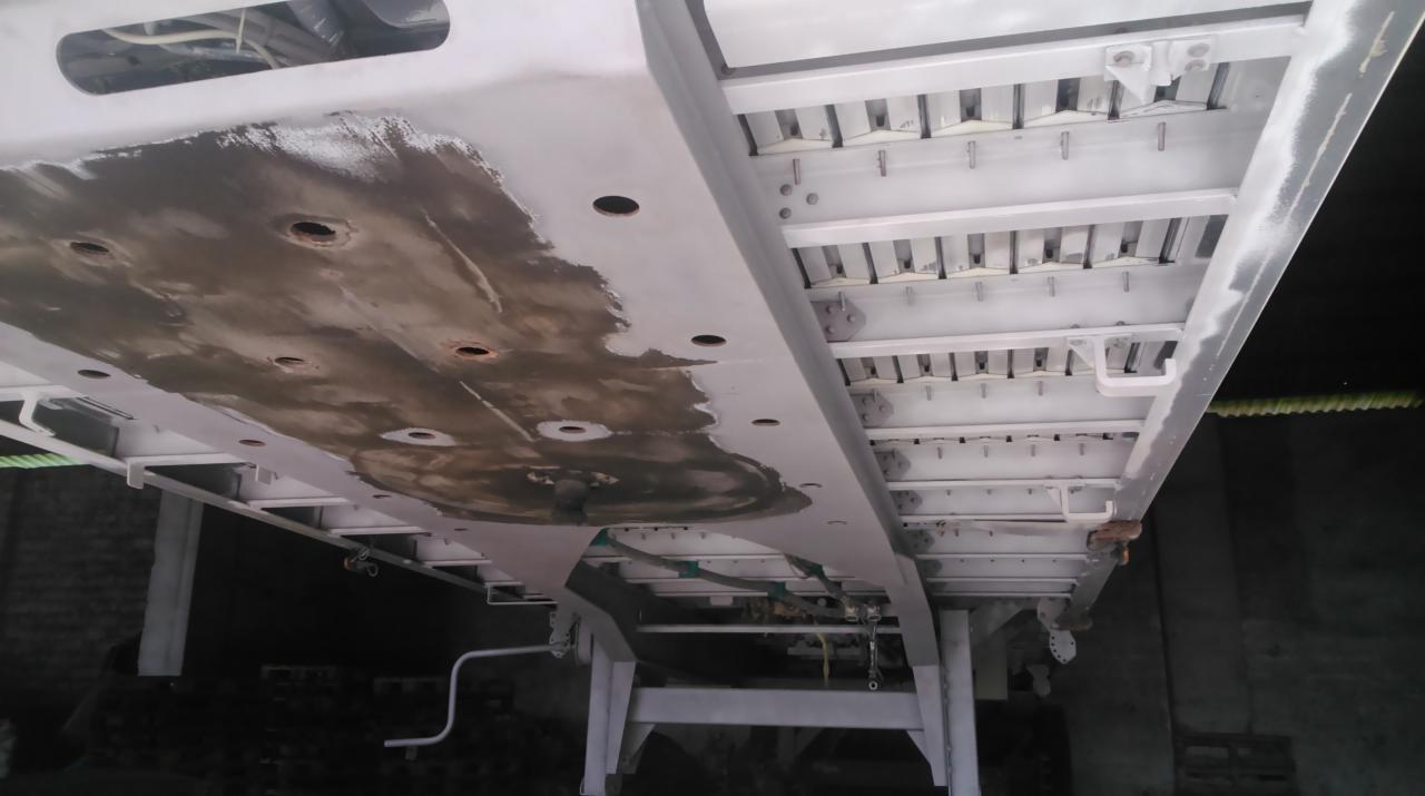 Metalowa konstrukcja poddana czyszczeniu, widoczne ślady korozji i pozostałości po procesie, częściowo pokryta świeżą, jasną powłoką ochronną.