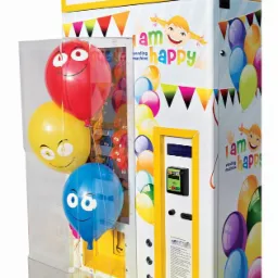 Automat vendingowy z balonami na hel z nadrukowanymi uśmiechniętymi twarzami, dekorowany rysunkami i napisem 'I am happy vending machine'.