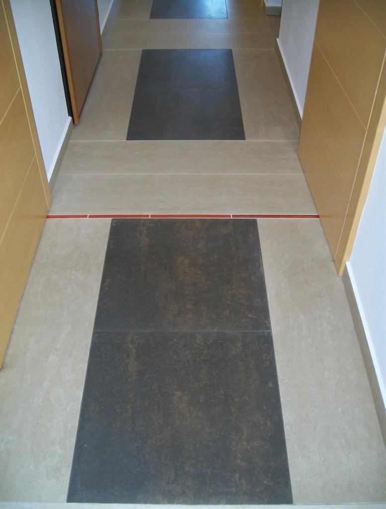 Ułożona podłoga z płytek w korytarzu w Bielsko-Białej, z ciemnymi kwadratami na jasnym tle, oddzielona cienką, czerwoną linią płytek.