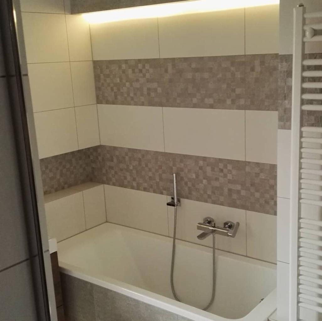 Wykończona łazienka z wanną, mozaikowymi pasami płytek i oświetleniem LED podsufitowym