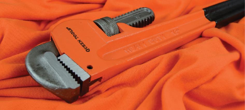 Pomarańczowy klucz nastawny marki Queen Tools leży na pomarańczowej tkaninie, widoczne detale zębów klucza i regulacji.