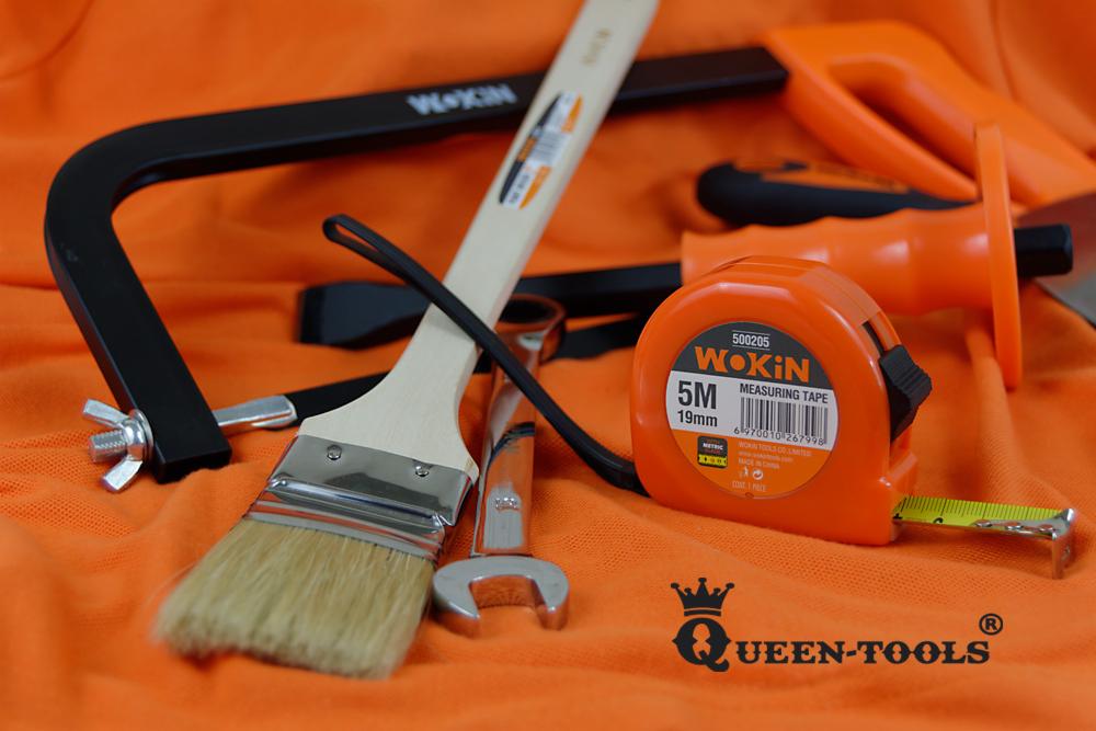 Zestaw narzędzi Wokin na pomarańczowym tle: piła do metalu, pędzel malarski, klucz płaski, miarka zwijana i dłuto.