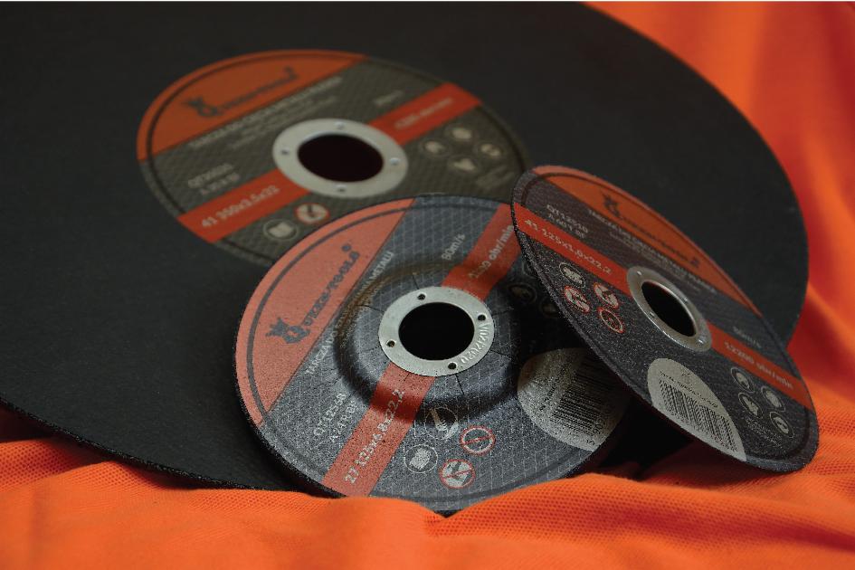 Trzy tarcze do cięcia metalu marki STIGGERTOOLS, o różnych rozmiarach i specyfikacjach, ułożone na pomarańczowym materiale, prezentujące detale techniczne i logo producenta.